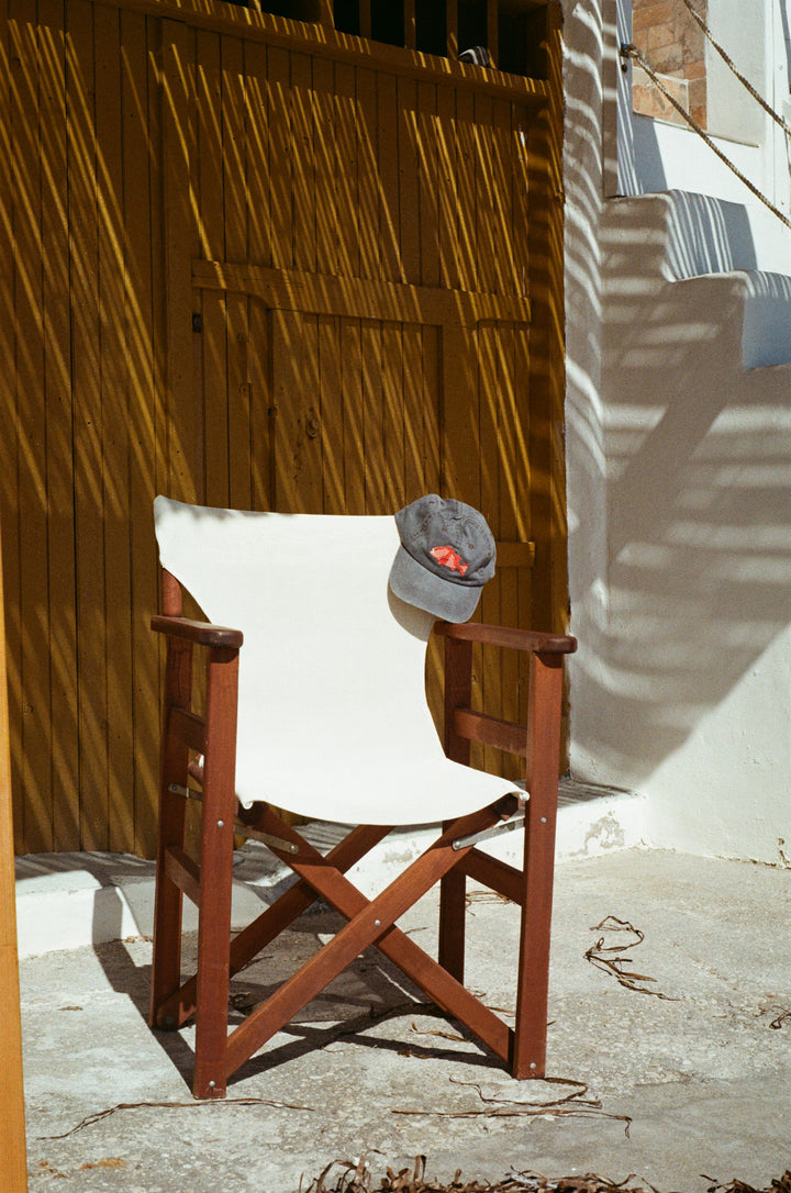 stone blue hat with a red fish embroidered on the front hung over a white director's chair