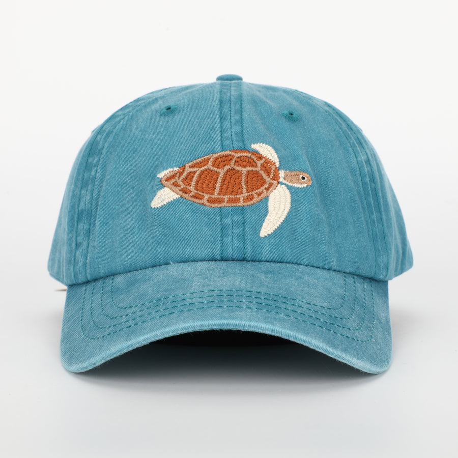 A sea turtle embroidered on a faded blue cap.